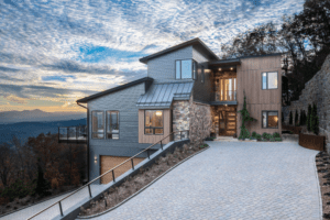 The Sennett Residence's modern-style front facade with clean lines and large glass windows, nestled against a mountain backdrop.