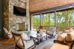 screened deck seating with large stone fireplace and mounted television