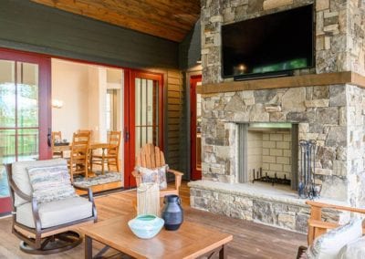 screened deck seating with large stone fireplace and mounted television