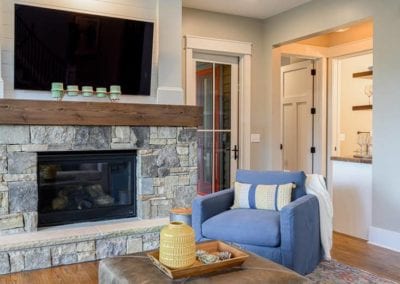 Stone cover fireplace with mounted television and thick wood mantle.