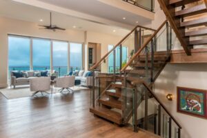 A staircase inside The Sennett Residence, surrounded by large windows offering scenic mountain views.