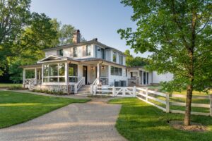 Side view of remodeled white house near Asheville, North Carolina, built by luxury home builder with energy-efficient features and original farmhouse aspects, showcasing locally milled wood and exposed beams.