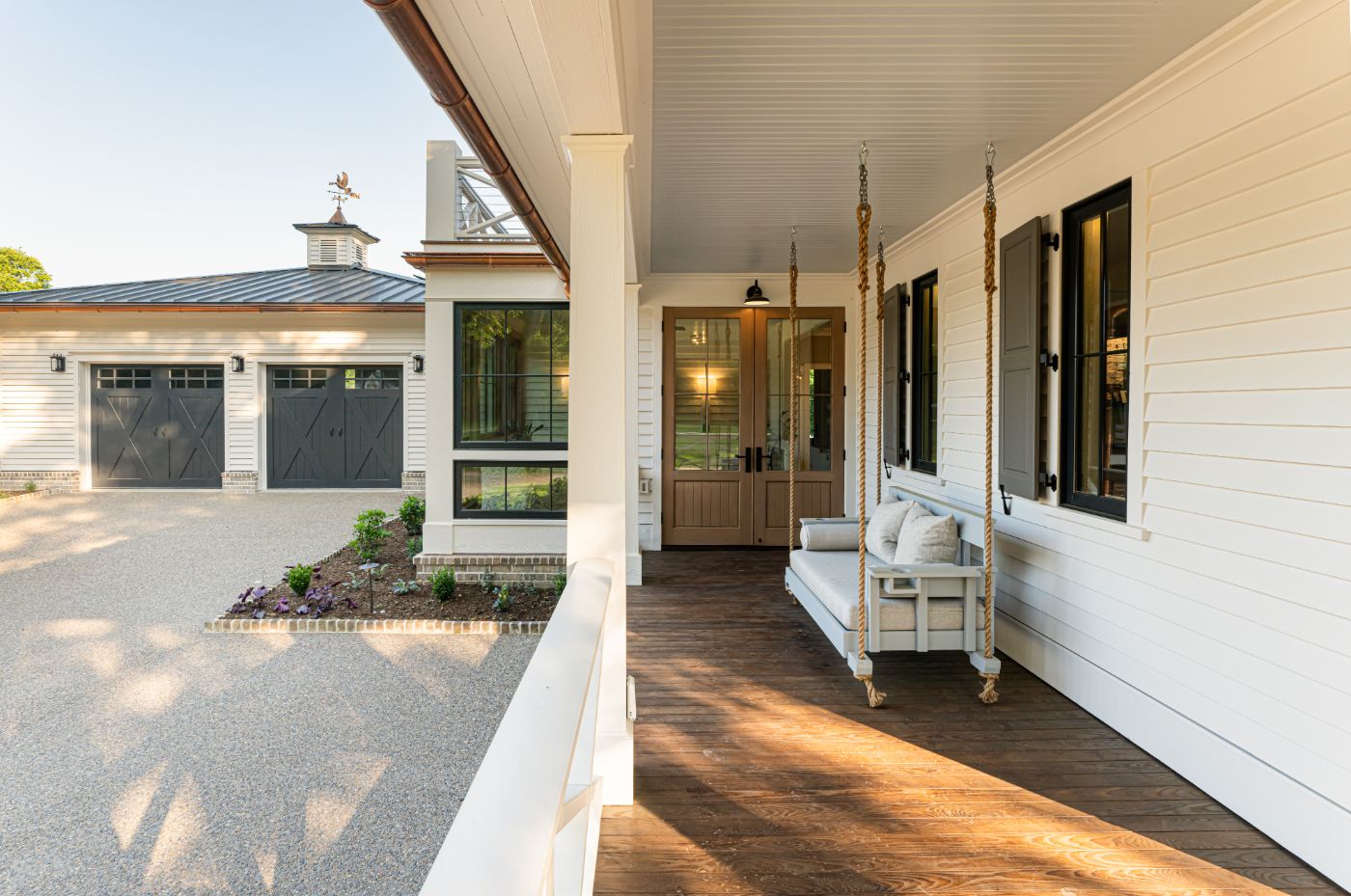 Remodeled Luxury Home with Custom Wrap-Around Porch and Porch Swing in Asheville, NC Custom wrap-around porch with porch swing, energy-efficient luxury home near Asheville, NC, featuring locally milled wood, exposed beams, and natural elements from original farmhouse.