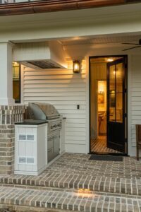 Side porch and grill of a remodeled house with whole-home renovation, near Asheville, North Carolina, built by a luxury home builder. Features locally milled wood, exposed beams, and energy-efficient design.