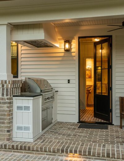 Side porch and grill of a remodeled house with whole-home renovation, near Asheville, North Carolina, built by a luxury home builder. Features locally milled wood, exposed beams, and energy-efficient design.