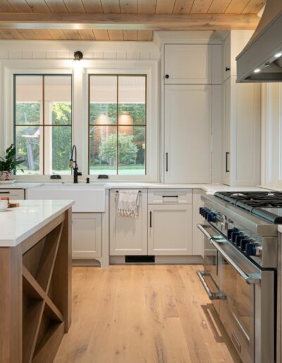 Remodeled kitchen with gas stove and island in a luxury home built near Asheville, North Carolina, featuring exposed beams, locally milled wood, and natural elements.