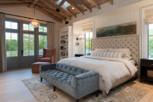 Master bedroom in a remodeled house with energy-efficient features, built by a luxury home builder near Asheville, North Carolina, incorporating original farmhouse aspects, locally milled wood, exposed beams, and natural elements.