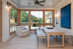 Sun room in remodeled house with whole-home renovation, energy-efficient, luxury home builder near Asheville North Carolina, featuring aspects of the original farmhouse, locally milled wood, exposed beams, and natural elements.