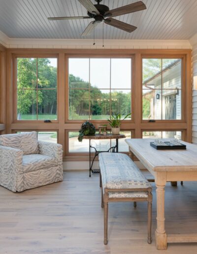 Sun room in remodeled house with whole-home renovation, energy-efficient, luxury home builder near Asheville North Carolina, featuring aspects of the original farmhouse, locally milled wood, exposed beams, and natural elements.