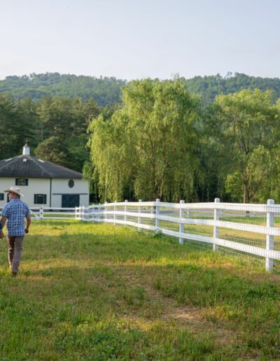 Luxury energy-efficient farmhouse with owners walking to barn, remodeled and renovated by a top builder near Asheville, North Carolina, featuring locally milled wood and natural elements.